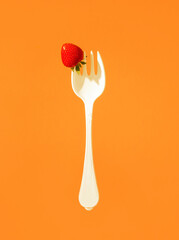 red ripe strawberries on a large plastic fork