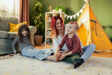 Mother and children playing and relaxing together in living room