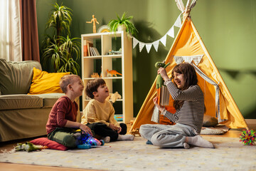 Girl playing puppet show for brothers in living room