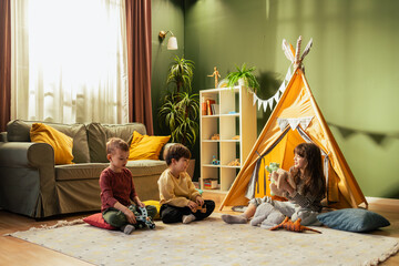 Children playing with toys in living room with teepee tent