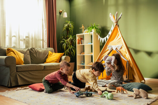 Children playing with toys in living room with teepee tent - Powered by Adobe