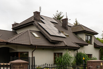 Solar panels on the roof of a private house. This residential installation on a dark, complex tiled roof features modern renewable energy technology for home sustainability.