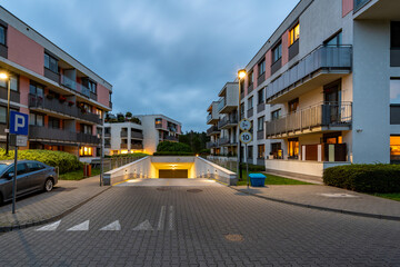 Underground garage entrance at a modern residential complex, illuminated at dusk. Offers residents convenient, secure parking, enhancing comfortable apartment living with well-kept grounds.