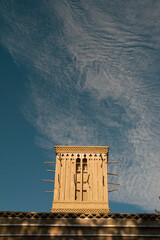 Traditional wind tower in Yazd, Iran, against a backdrop of wispy clouds and blue sky, showcasing ancient Persian architecture.