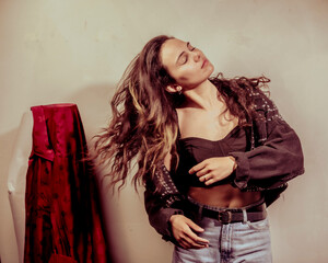 The image captures a young woman in a stylish outfit, looking confident with flowing hair,...