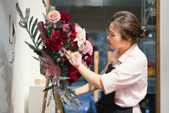 Floral designer arranging a vibrant bouquet in a stylish workshop during daylight