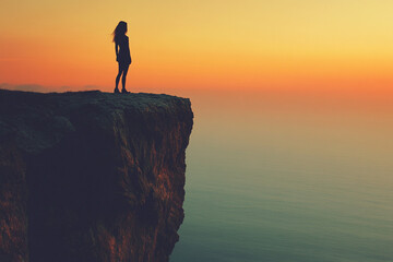 Woman standing at the edge of a cliff