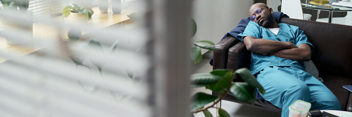 African American medical professional sitting in chair resting after long shift with arms folded...