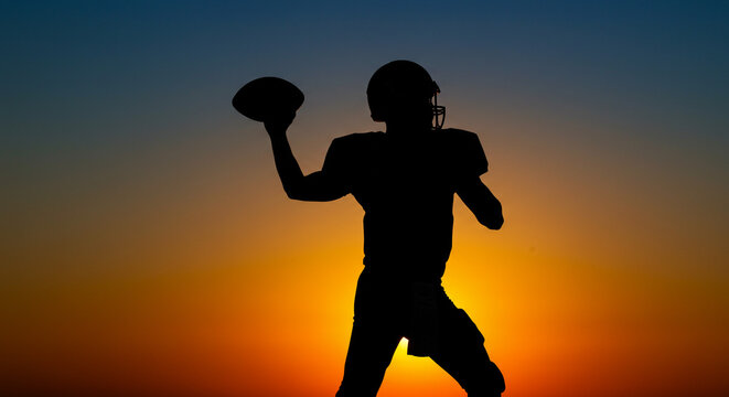 Silhouette of football player throwing ball during sunset with orange and blue sky in the background