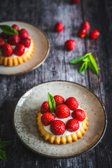 Homemade strawberry tartlets on dark wooden table