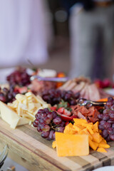 cheddar cheese, grapes, and other fruit and charcuterie being served on platter at outdoor cocktail hour