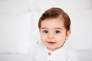a baby, a close-up portrait of a smiling or laughing baby boy on a white bed, a place for text