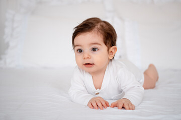 a baby on a white bed at home, a place for text, a cute smiling little child getting ready for bed, a portrait of a little boy child
