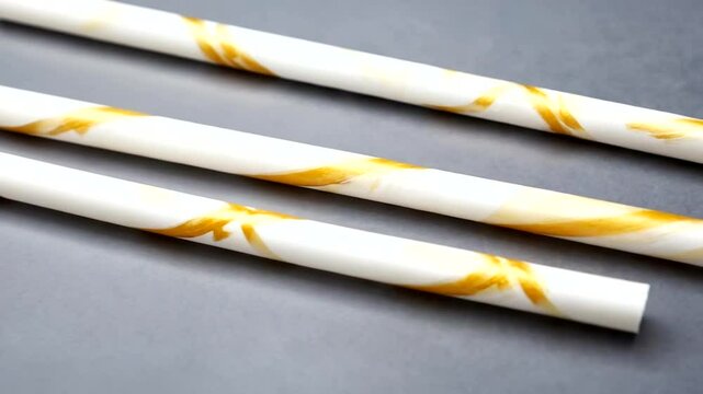 Elegant white and gold marbled straws arranged on a gray background, perfect for festive occasions
