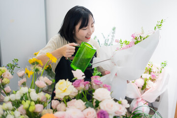 Young woman joyfully arranging colorful flowers in a floral shop during daytime, showcasing her...