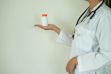 An asian young doctor with stethoscope is holding an medicine bottle to assess the quality of...