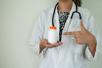 An asian young doctor with stethoscope is holding an medicine bottle to assess the quality of...
