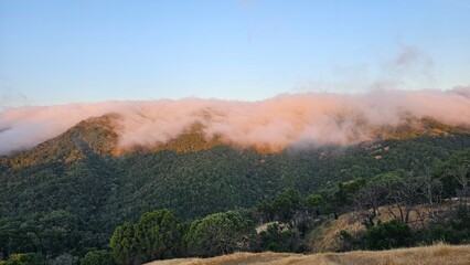 Blanket of fog rolling over a mountain ridge at sunrise