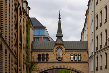 Historic pedestrian bridge with arched windows and a pointed tower connecting two classic brick buildings in European city. Traditional European architecture, heritage and urban aesthetics