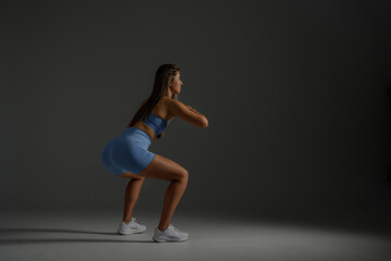 Fitness enthusiast performing squats in a minimalist studio setting during evening hours