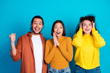 Excited diverse group of friends expressing surprise and happiness together against a vibrant blue background in casual outfits