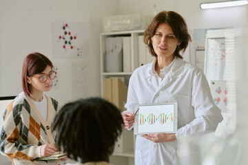 Scientist explaining genetic research to students in modern laboratory. Showing DNA structure on...