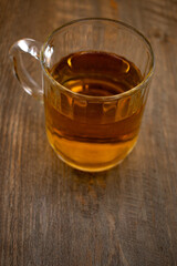 a clear glass mug of green tea, centered on a rustic wooden surface with scattered tea leaves, evokes a sense of calm and natural purity. Ideal for wellness, mindful living, or beverage themes