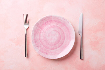 Empty Pink plate and cutlery on the pink background. Perfect for romantic dinner, Valentine Day, anniversary or Birthday. Copy space. Flat-lay, top view.