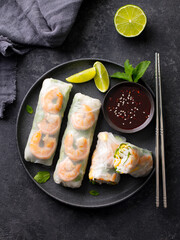 Vietnamese spring rolls with shrimps and vegetables on a black plate. Grey background. Close up. Top view.