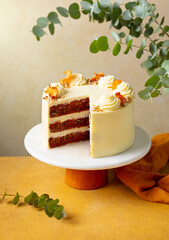 Carrot cake with cream cheese and pecan nuts. Beige and yellow background. Copy space.