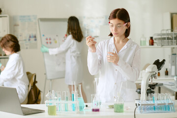 Researchers in white lab coats conducting experiments in chemistry lab. Student preparing chemical...