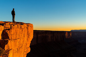 Man standing on the edge of a canyon silhouette