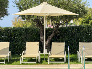 Sunbeds and umbrella by the pool water, Sunny day. Summer holidays