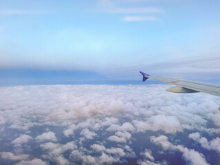 Plane flying over clouds, aerial view from airplane window, fluffy cloudscape and blue sky