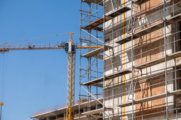 Building construction site, scaffolding system and tower crane, under construction project