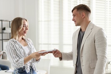 Money bonus. Boss giving envelope to employee in office