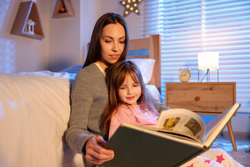 Mother reading bedtime story to her daughter at home