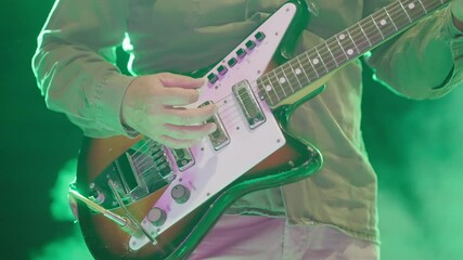 Guitarist musician hand playing an electric solo guitar under vibrant stage lights on concert, slow motion