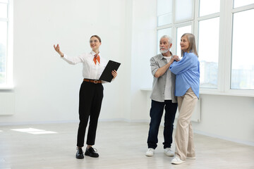 Fototapeta premium Smiling real estate agent showing apartment to couple indoors