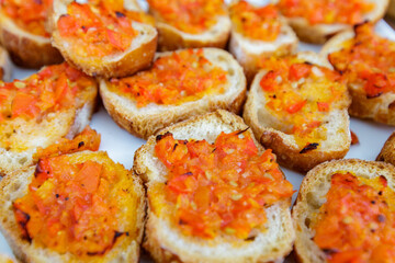 fresh and savoury tomato bruschetta, italian appetizers, called antipasto, with mashed tomatoes, olive oil, basil, spread on a small roasted slice of bread