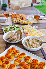a welcoming wooden table covered with savoury appetizers, called antipasti, on an outdoor terrasse, during european summer