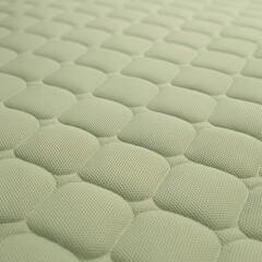 Obraz premium A soft, macro close-up of a padded textile surface in light sage green color, featuring a rounded hexagonal (honeycomb-like) quilted pattern.