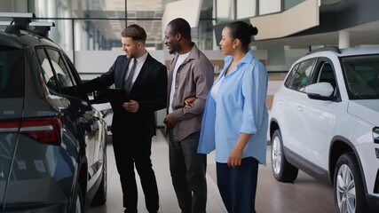 Car salesman showing a new car to african american couple - Powered by Adobe