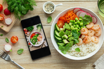 lunch bowl and smartphone with picture of dish on wooden table