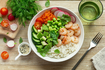 lunch bowl with rice, shrimps, avocado, cucumber, edamame beans radish and tomato in white bowl