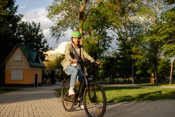 Obraz premium Bicyclist enjoying evening ride in urban park with green trees and warm sunlight