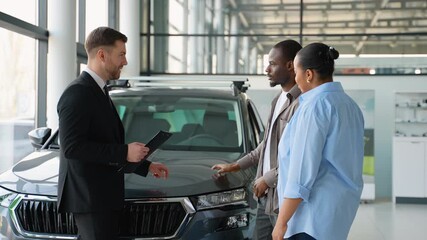 Car salesman showing new car to african american couple