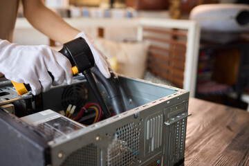 A man cleans a computer case with a vacuum in a bright room, stressing workspace tidiness