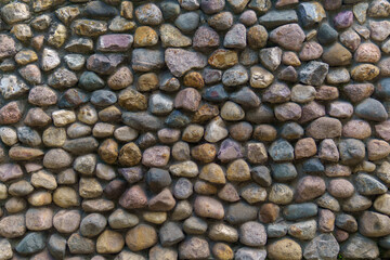 Wall fence of stones of different sizes roughly stacked on top of each other and fastened with cement. Construction industrial background.