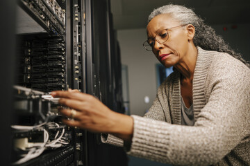 Middle-aged Black woman handling an IT upgrade, installing new software and configuring workstations for her department